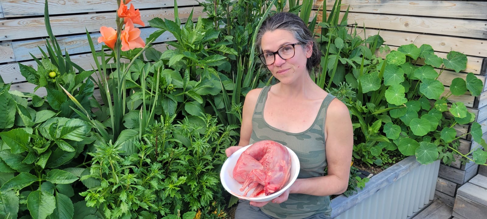 Holding a freshly processed rabbit, surrounded by flowers in the garden